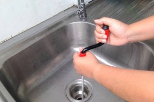 Woman's hand are breaking through the pipes. Clog pipe cleaner by yourself. Flexible spring drain cleaner.