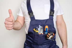 Construction worker with tools in his pocket against white background